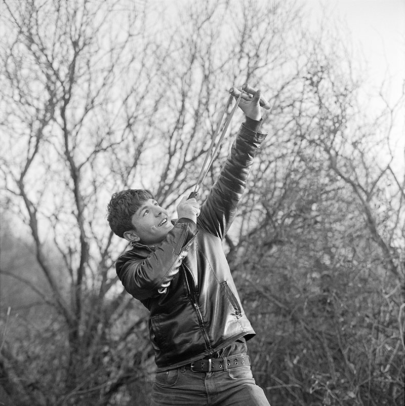 Un garçon tire au lance-pierre pour la photographie, Jungle de Calais, 2016